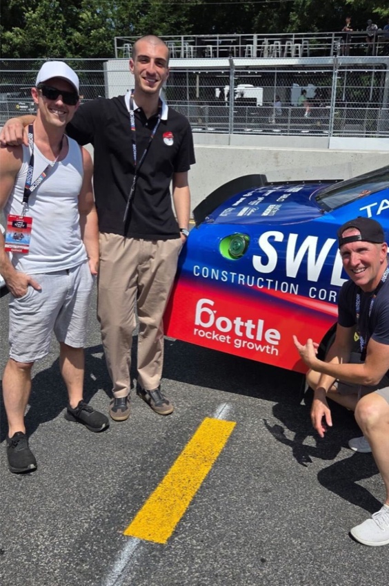 Three people beside the number 71 race car with Bottle Rocket Growth branding